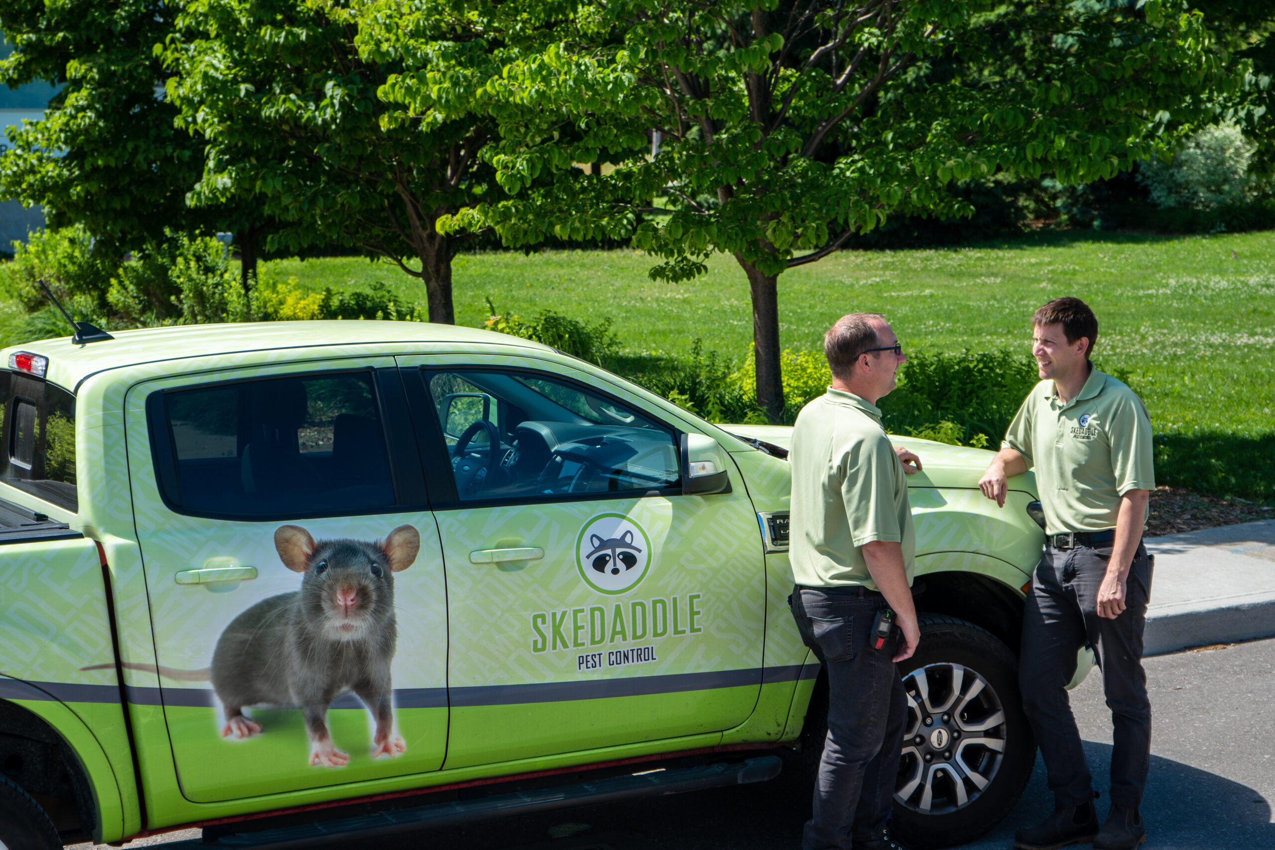 Skedaddle Pest Control Professionals Conversing Next to Branded Truck