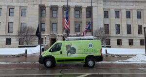 A branded Skedaddle wildlife control truck parked on the street in front of the Columbus City Hall building.