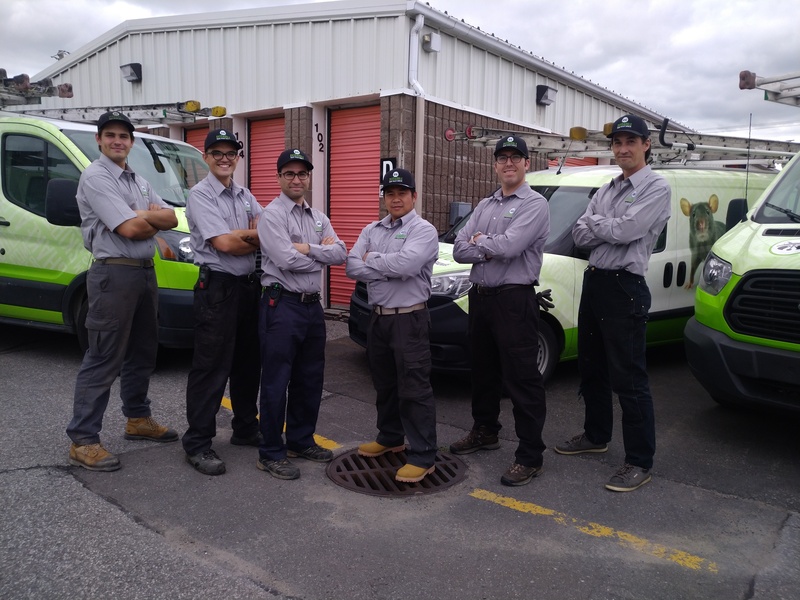 Six Skedaddle in Montreal standing in uniform outside with company service vans