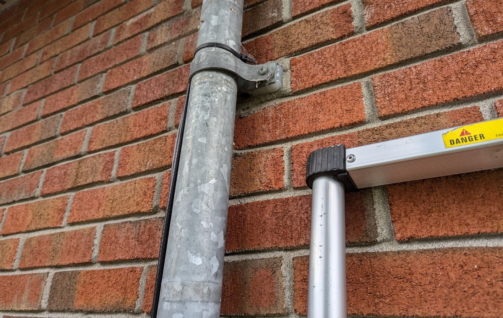 Galvanized Metal Downspout and Ladder Along Exterior Brick Wall